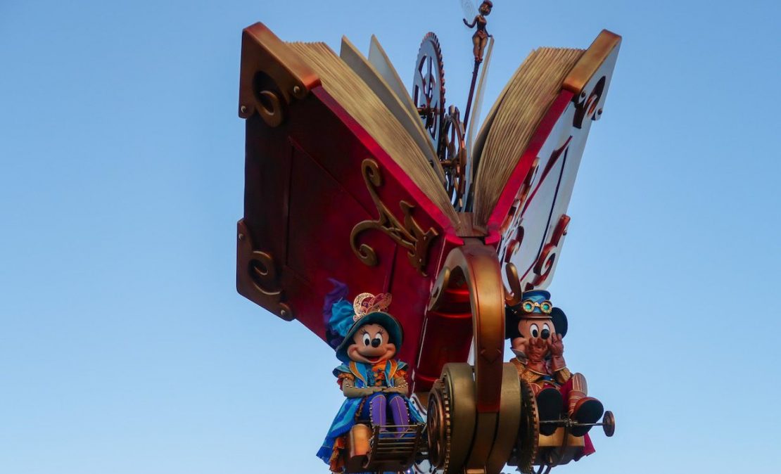 Mickey Mouse y Minnie Mouse saludando desde una carroza colorida en la cabalgata de Disneyland Paris.