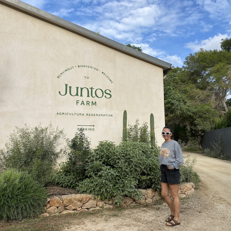 Mónica posando junto al letrero de Juntos Farm en Ibiza.
