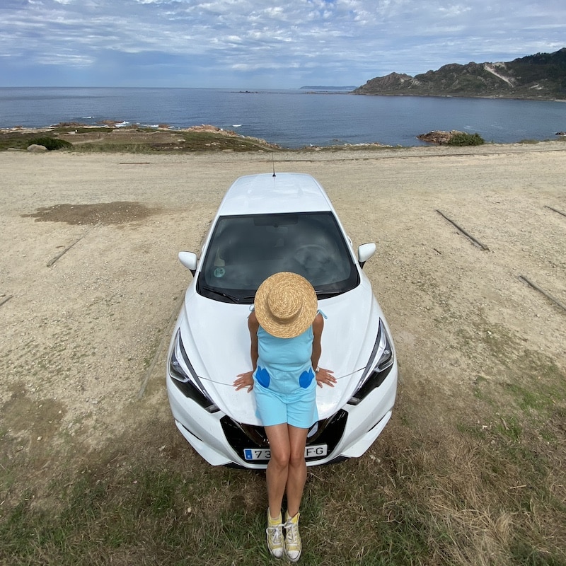 Mónica apoyada en un coche de alquiler durante una ruta por la Costa da Morte en Galicia.