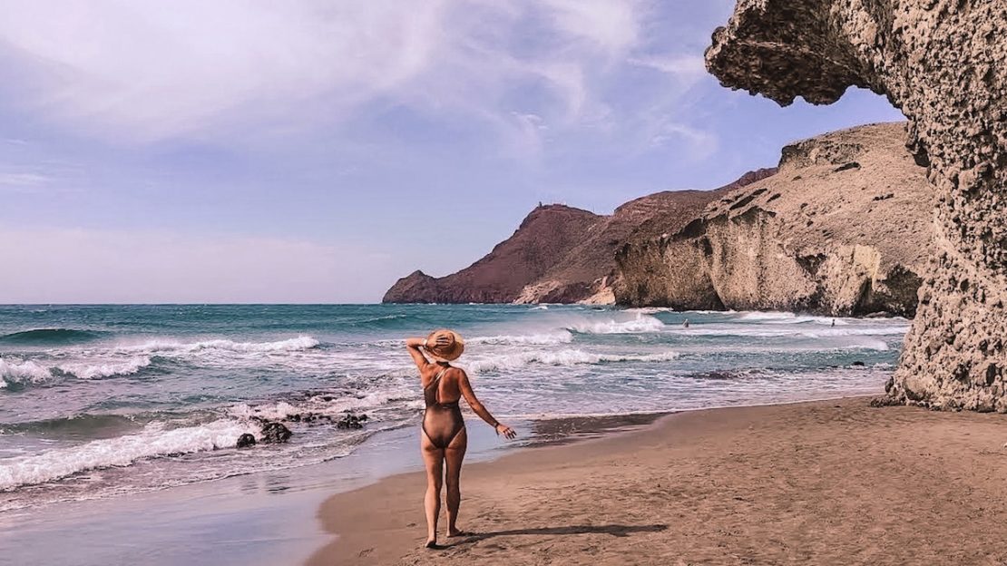 Mónica paseando por la playa de Mónsul en Almería con sombrero de paja y viento