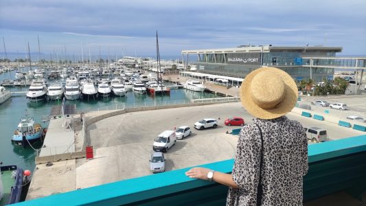 Mónica de El Viaje de Sofía en la cubierta de un ferry de Balearia viendo el embarque de coches hacia Mallorca.