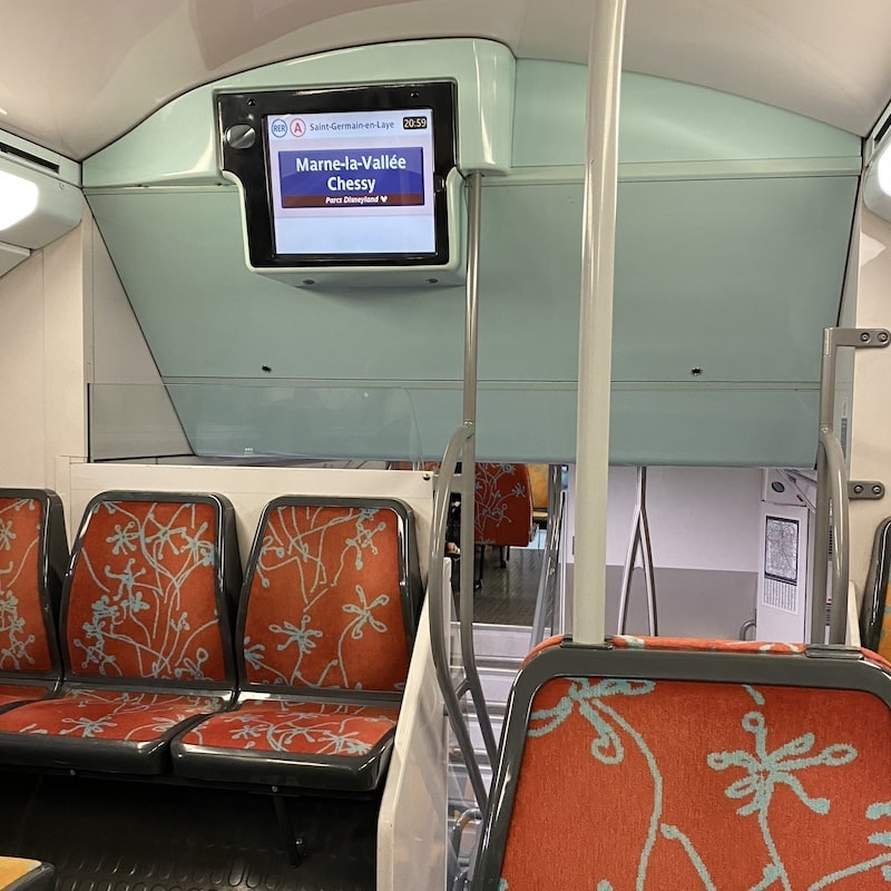 Interior de un tren RER A con pantalla digital indicando el destino final Marne-la-Vallée Chessy (Disneyland).