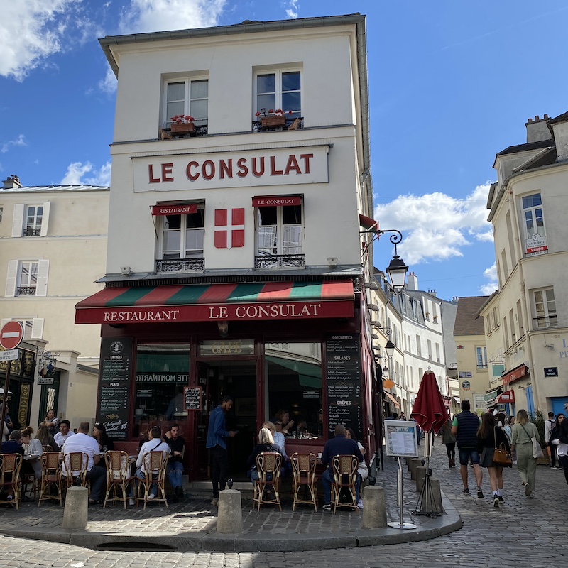 Fachada del café Le Consulat en Montmartre con su característico estilo bohemio y ambiente artístico