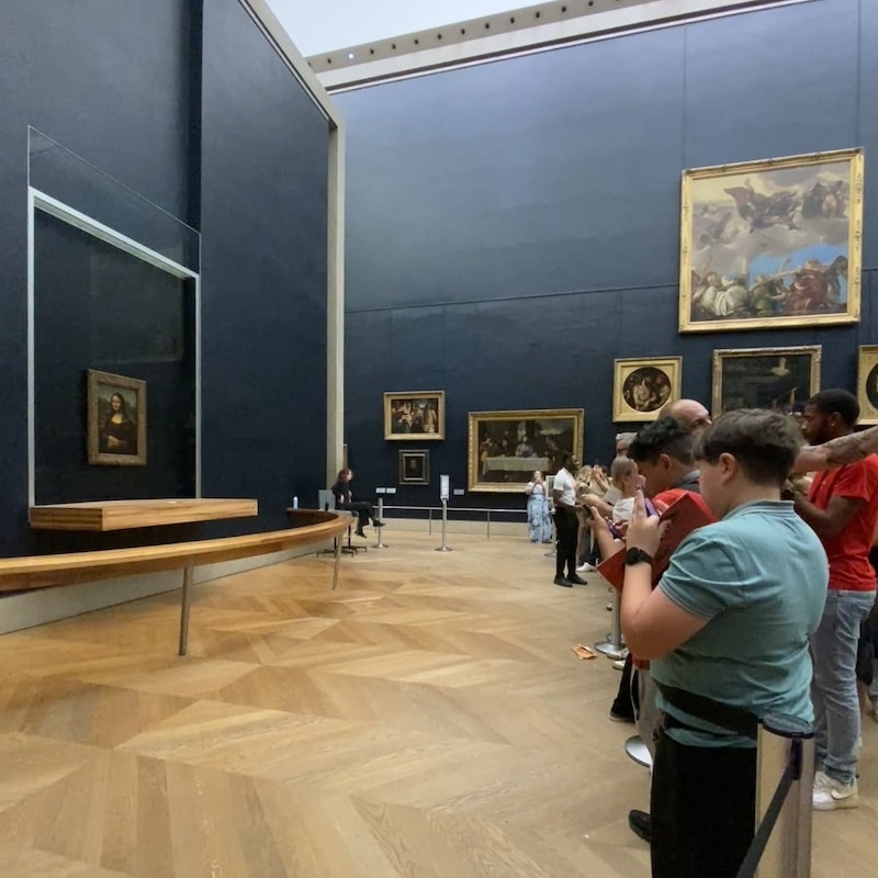 Multitud de turistas con teléfonos móviles fotografiando la Mona Lisa de Leonardo da Vinci en la Sala de los Estados del Louvre.