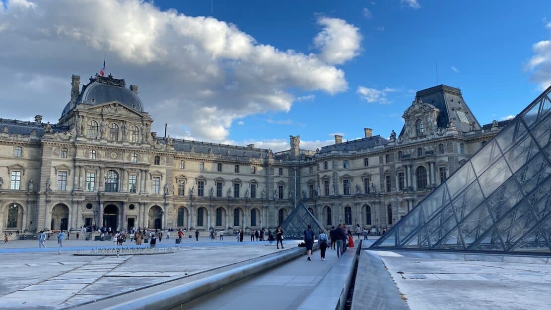 Vista exterior de la pirámide de cristal del Museo del Louvre en París con turistas para la ruta de dos horas.