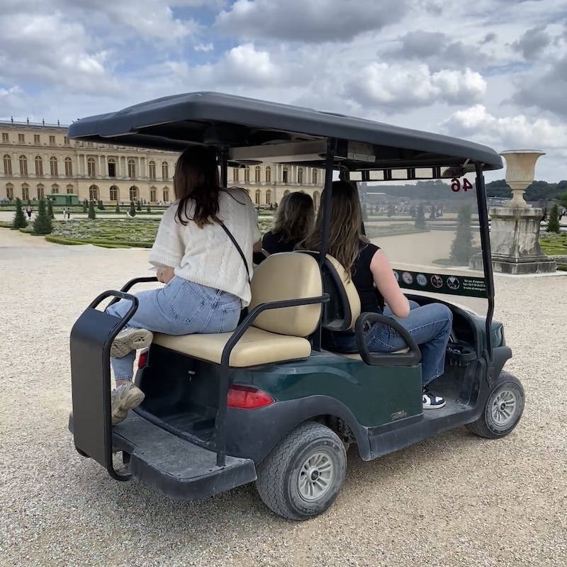 Carrito de golf eléctrico circulando por los senderos de los jardines de Versalles.