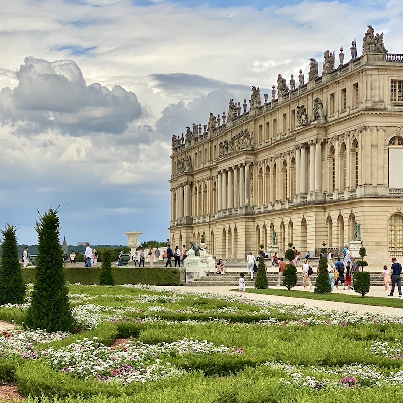 Vista de los jardines de Versalles con setos perfectamente cortados y el palacio al fondo.