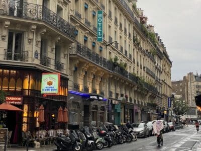 Fachada de hotel en una calle típica de París con arquitectura Haussmann, transmitiendo ambiente parisino.