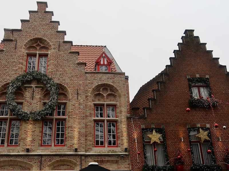 Dos fachadas típicas de Brujas decoradas con luces navideñas