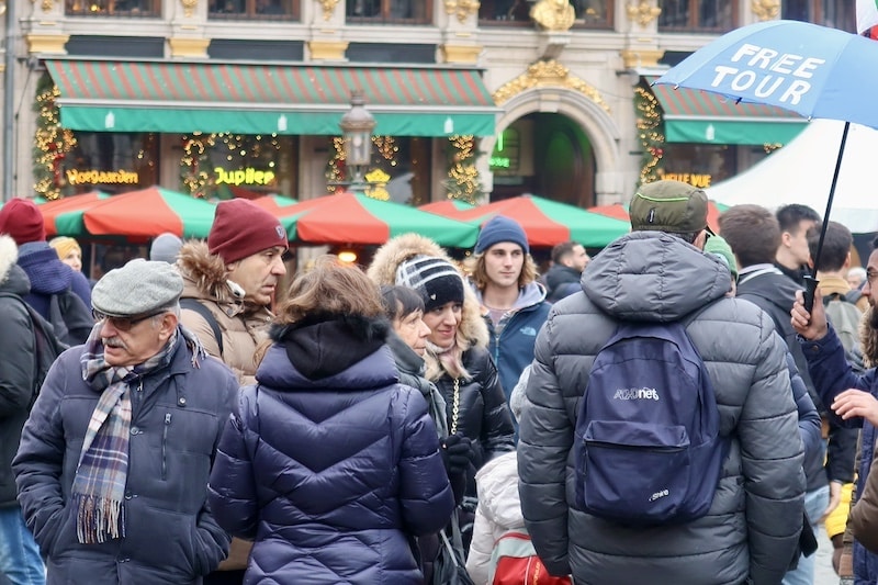 Visitantes parados en una plaza de Bruselas con decoración navideña y guía de free tour