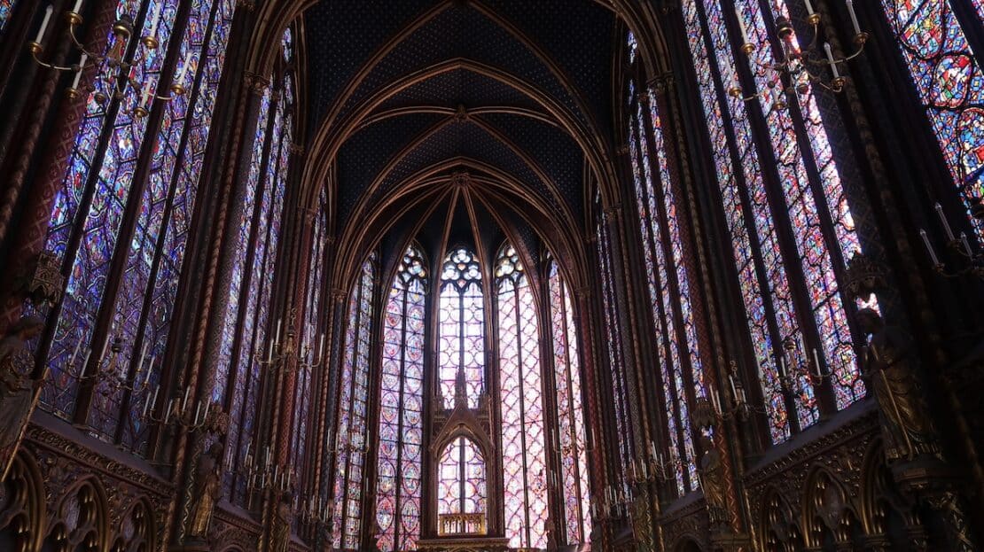 Vidrieras góticas del ábside en la sala alta de la Sainte-Chapelle de París, destacando el color azul y la luz natural.