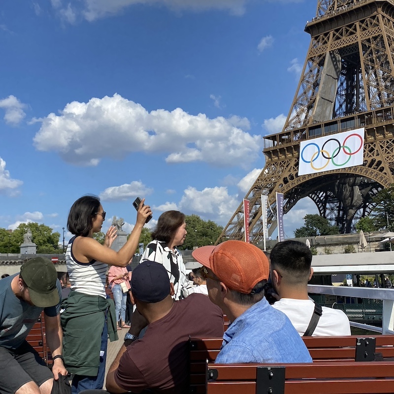 Cubierta superior de un crucero por el Sena llena de turistas haciendo fotos con el móvil.