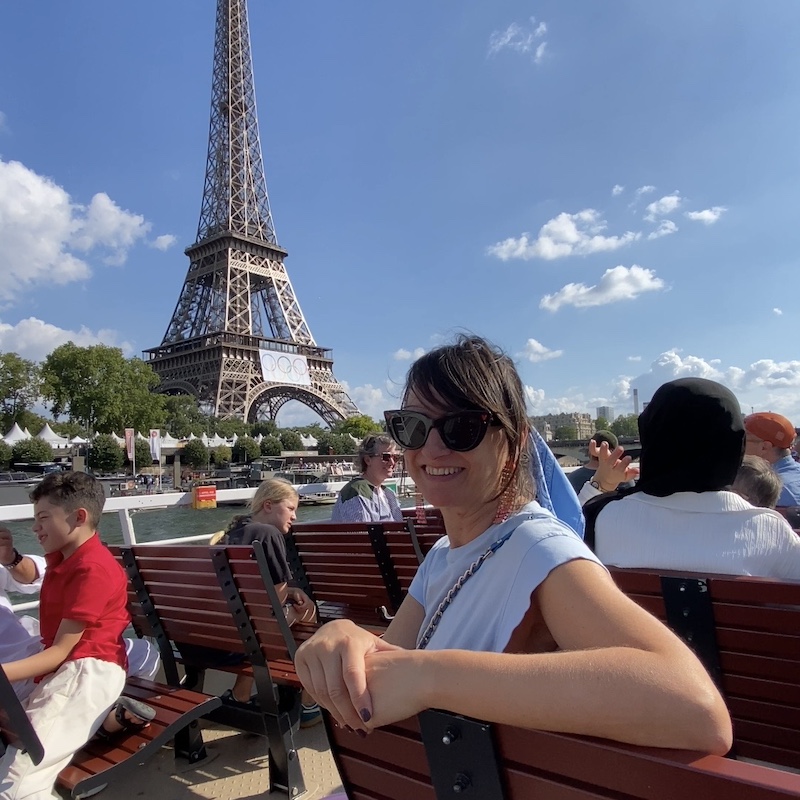 Mónica sonriendo en la cubierta de un crucero por el Sena con la Torre Eiffel de fondo.