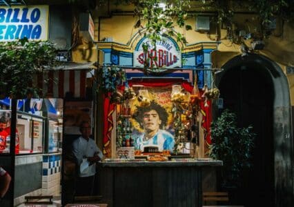 Fachada de la Pizzería Sorbillo en Nápoles con mural de Maradona y productos típicos de street food