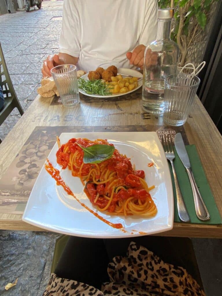 Plato tradicional de polpette al sugo y espaguetis en una terraza típica donde comer en Nápoles comida casera