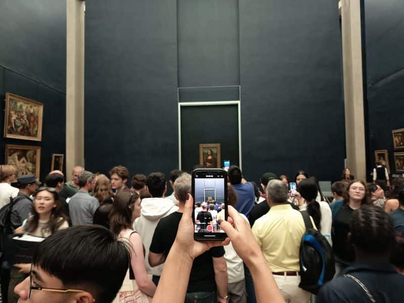 Intentando hacer una foto a la Gioconda (Mona Lisa) de Da Vinci entre una multitud de turistas en el Museo del Louvre, París.