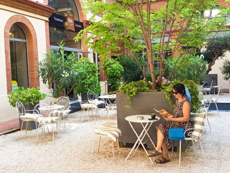Mónica en una mesa de la terraza del patio interior del hotel Ibis Styles Toulouse Capitole en Francia.
