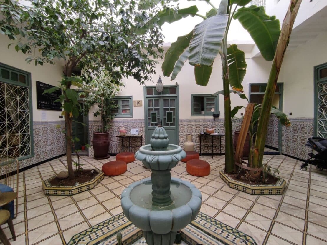 Patio del Riad Orange en Marrakech rodeado de naranjos y luz natural.