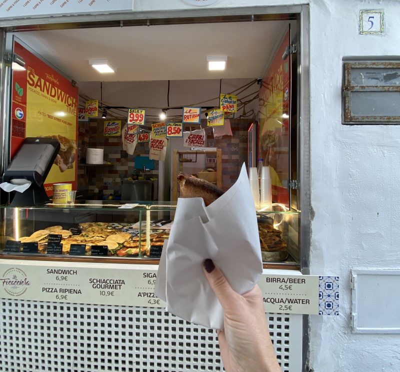 Puesto de comida para llevar en Capri con precios de porciones de pizza y sándwiches
