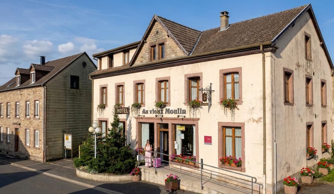 El Viaje de Sofi (Mónica) con maleta entrando al hotel Au Vieux Moulin en Alsacia Francia.