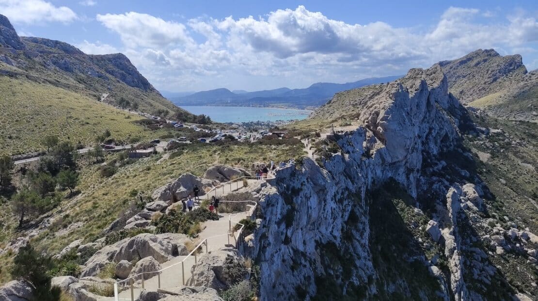 Carretera panorámica hacia el Cabo Formentor con coches aparcados y vistas al mar en Mallorca.