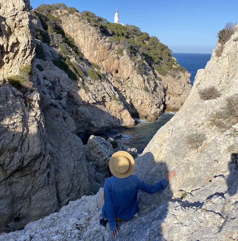 El Viaje de Sofi (Mónica) en el acantilado de Cap de Pera con vistas al mar y al faro, Mallorca.
