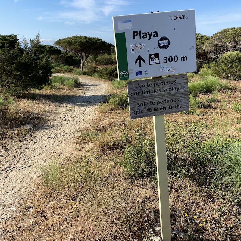Cartel informativo de madera señalizando el acceso a la playa a 300 metros en una zona natural de Cádiz.