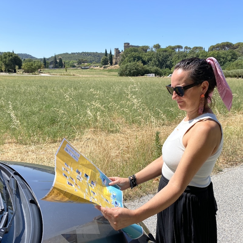 Un coche de alquiler aparcado en una carretera secundaria rodeada de viñedos y colinas en la Provenza.