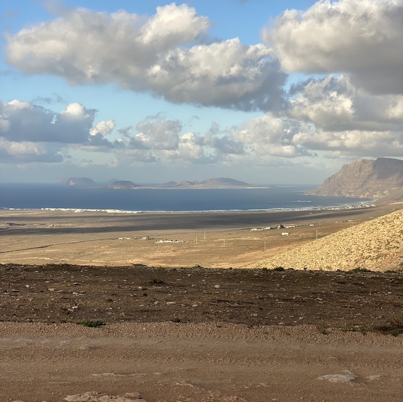 pista de tierra en el norte de Lanzarote con volcanes y playa al fondo