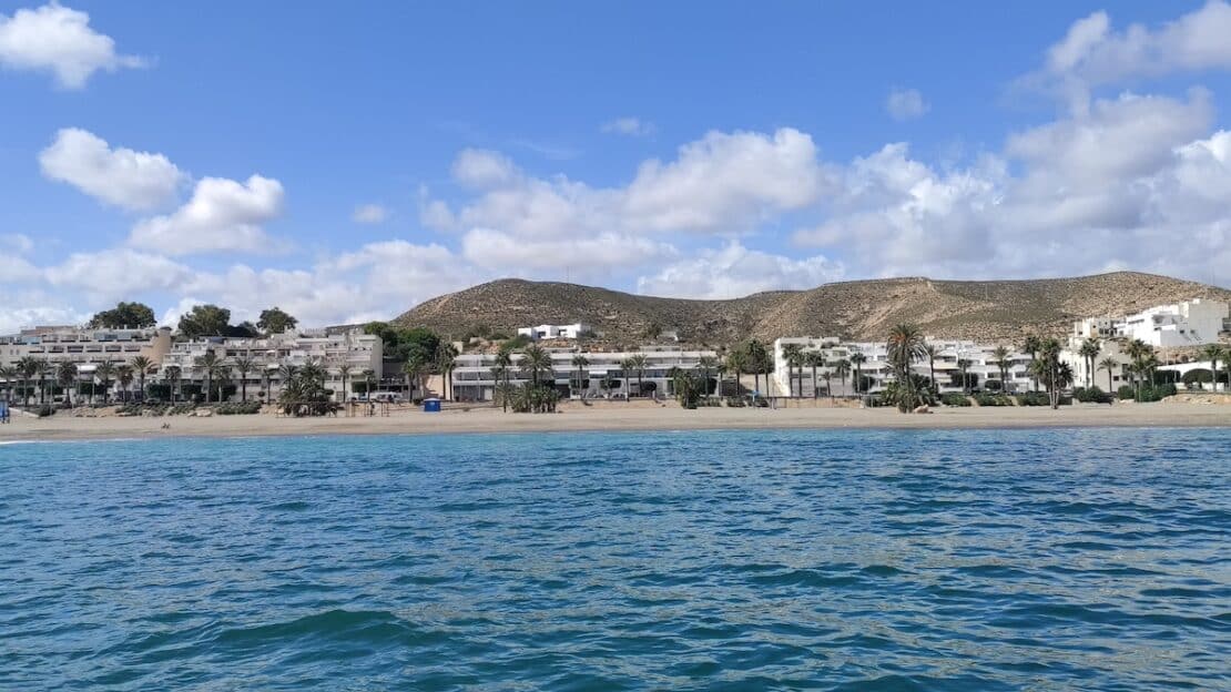 Vista panorámica de hoteles blancos en primera línea de playa en Cabo de Gata, Almería, frente al mar Mediterráneo azul.