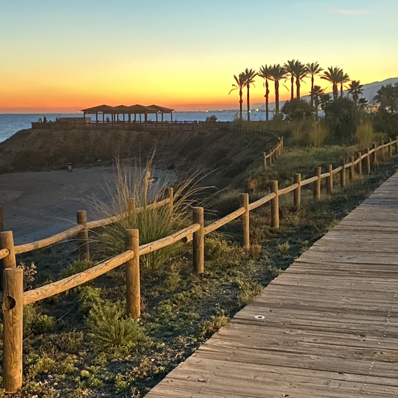 Puesta de sol espectacular sobre la playa de Retamar en Almería, con el cielo naranja reflejado en el mar.