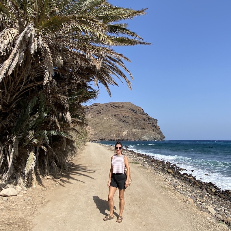 Paseo diurno por el pueblo costero de Las Negras, Cabo de Gata, con palmeras y el mar.