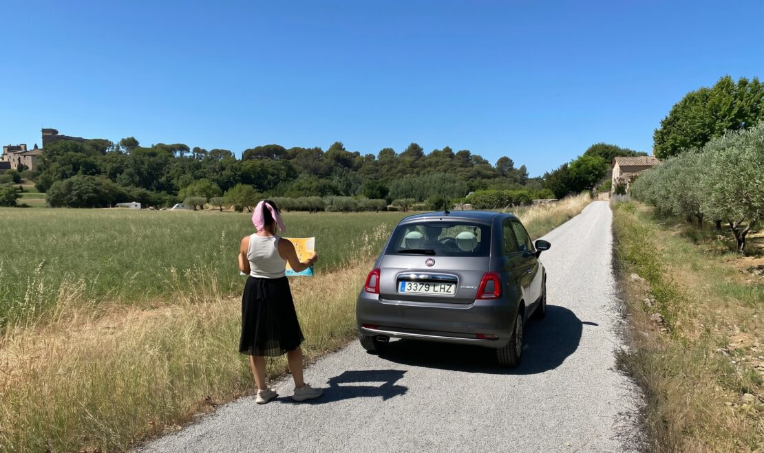 Viajar por Francia en coche o tren: ruta por carretera con coche propio y mapa frente a un castillo medieval