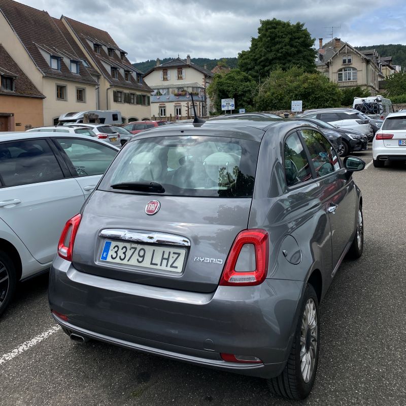 Coche de alquiler gris aparcado en un parking público exterior en un pueblo de Alsacia