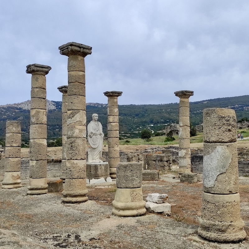 Columnas de piedra y estatua de Trajano en el foro del Conjunto Arqueológico de Baelo Claudia.