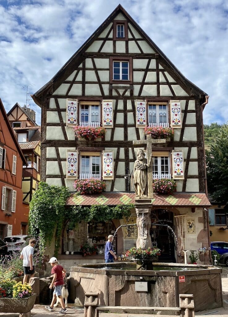Fachada de entramado de madera de la Maison Liewer y la Fontaine de Constantin en la Plaza de la Iglesia de Kaysersberg.