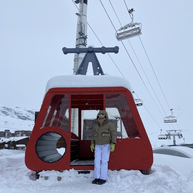 Mónica de El Viaje de Sofi junto a una antigua telecabina roja en la estación de esquí de Val Thorens en los Alpes franceses